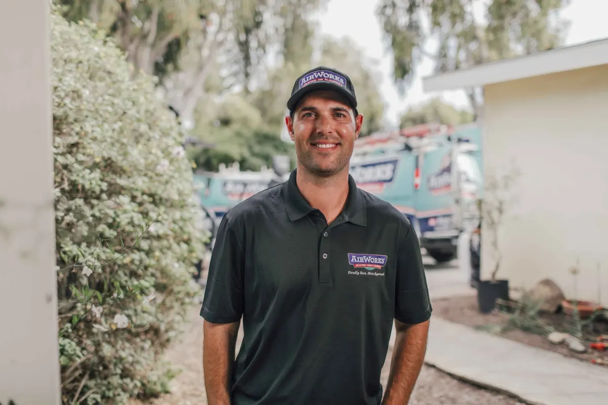 AirWorks team member in uniform standing in front of the branded service trucks